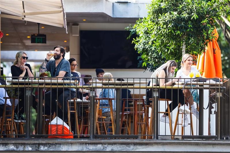 Groups of people enjoy a drink on a balcony.