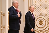 Lukeashenko and Putin walk through a set of ornate doors in white and gold.