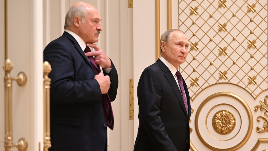 Lukeashenko and Putin walk through a set of ornate doors in white and gold.