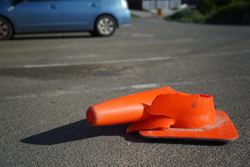 A squashed orange witches hat traffic cone on a road