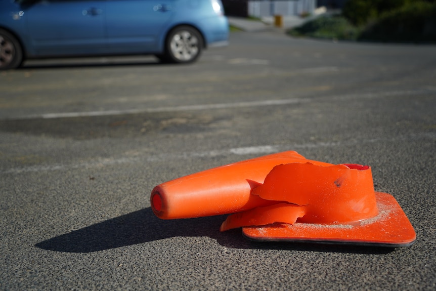 A squashed orange witches hat traffic cone on a road