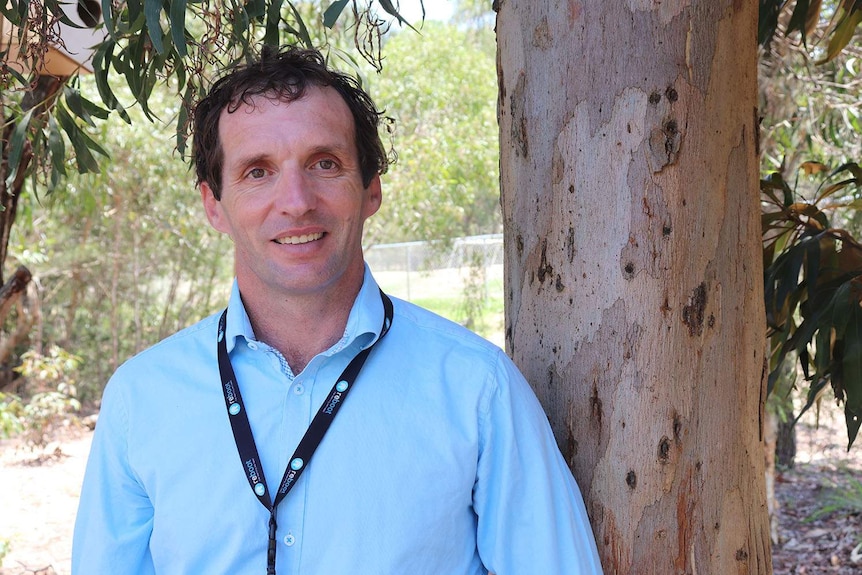 Stephen Kanowski, stands next to a tree in the school grounds in the Logan school.