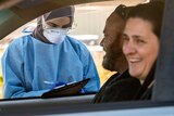 a person in PPE taking the details of a couple laughing a car