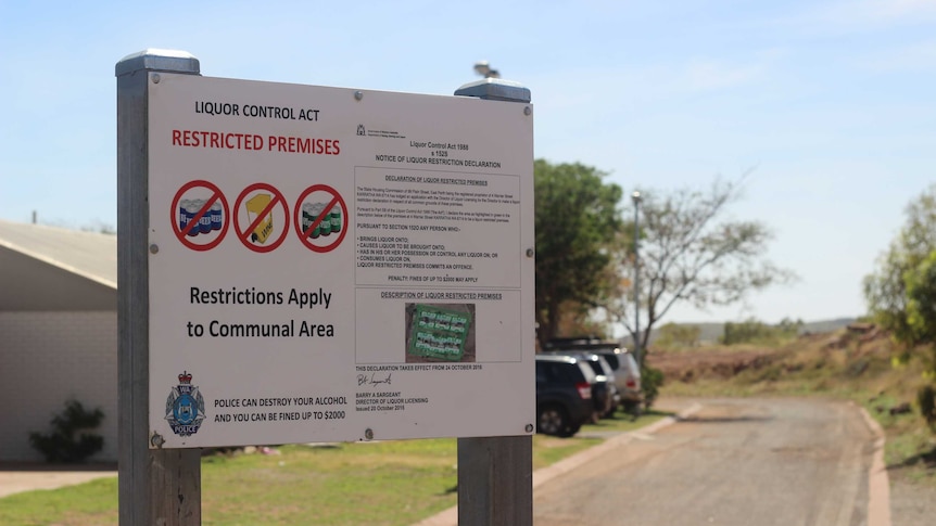 A sign in front of public housing complex states that liquor restrictions apply to the premises and $2,000 fines can apply