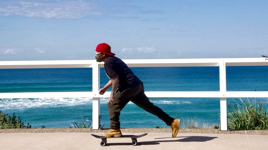 A skateboarder wearing a mask at the beach.