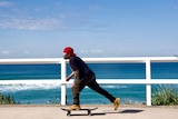 A skateboarder wearing a mask at the beach.