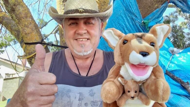 man in straw cowboy hat with grey goatee beard giving thumbs up with kangaroo puppet on other hand