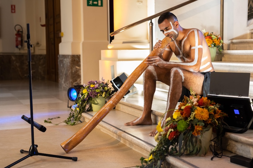 Jack Collard plays the didgeridoo while sitting on the steps at the Brussels Art and History Museum. 