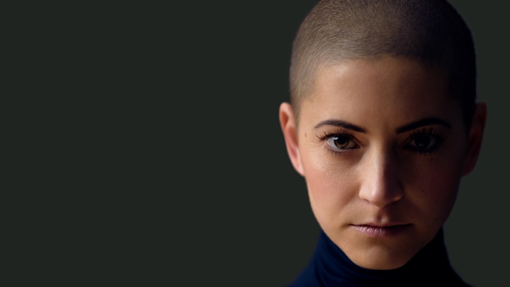 Woman with very short hair against dark background