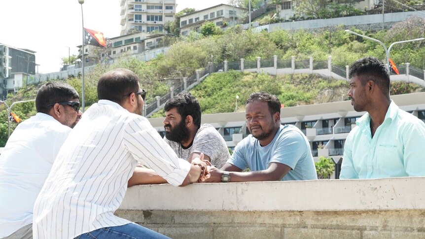 Sri Lankan refugees sit around a stone outdoors table in Port Moresby. They were previously held on Manus Island.