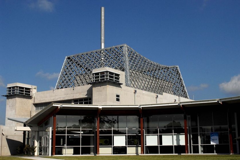 A large, concrete building with a mesh-looking structure on top.