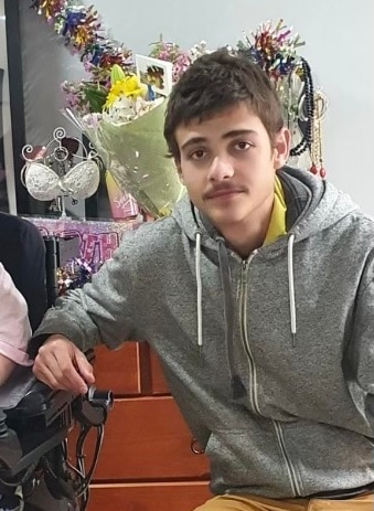 A close up of a young man with brown hair and a moustache.