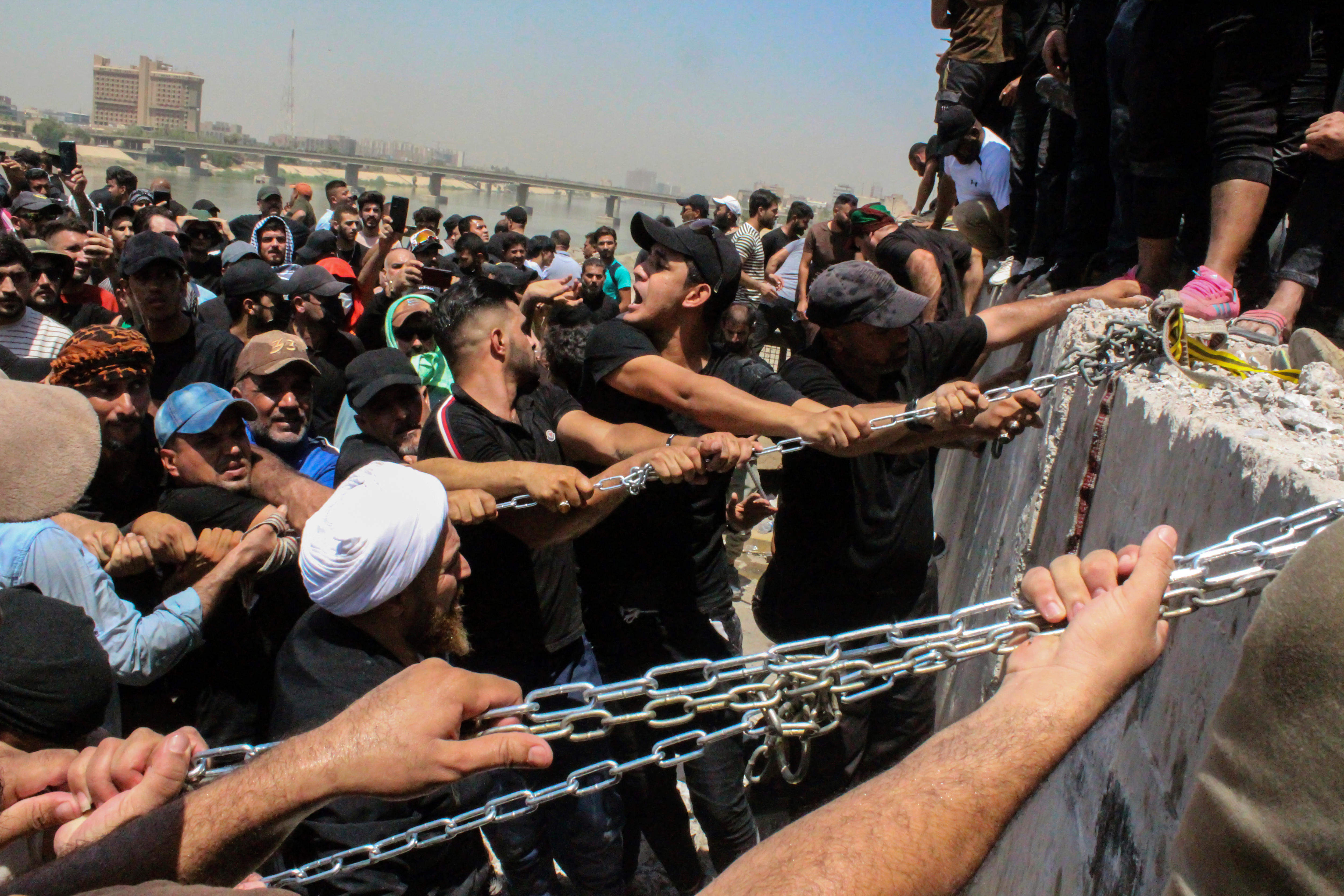 Men dressed in black use chains to tear down concrete barricades.