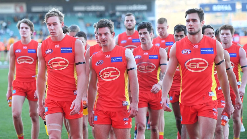 Gold Coast players look downcast as they leave the field