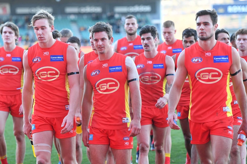 Gold Coast players look downcast as they leave the field