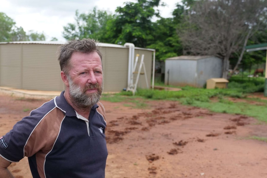 Katherine landowner Anthony Bartlett is standing in front of a rainwater tank on his property.