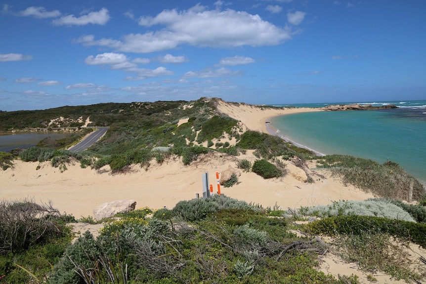 A landscape shot of a beach dune being eroded with a road on the left on the image