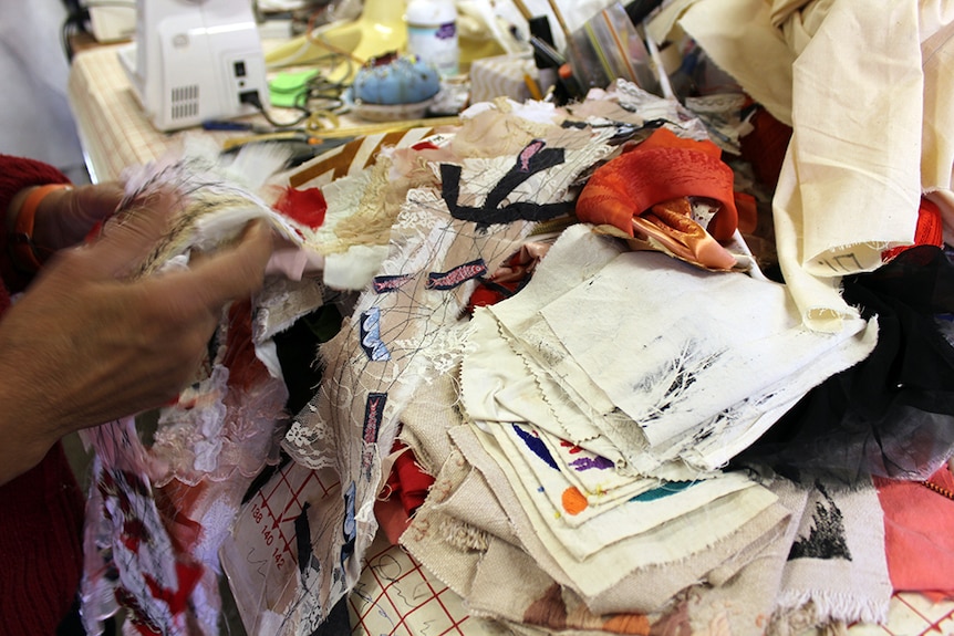 A close-up of samples of material, with a sewing machine in the background.