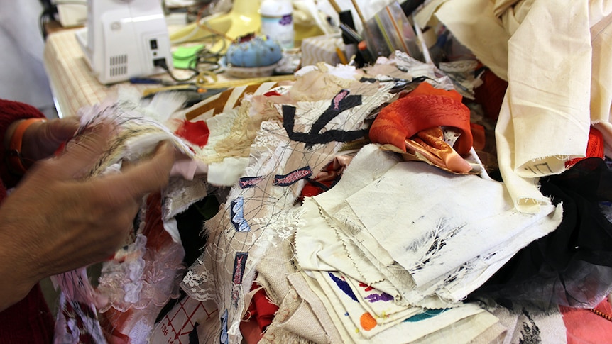 A close-up of samples of material, with a sewing machine in the background.