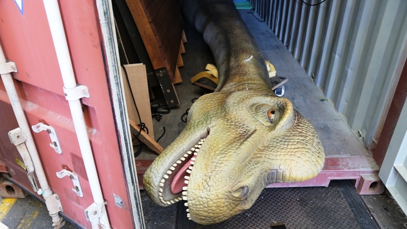 One of the dinosaur heads sticking out of the back of a shipping container.