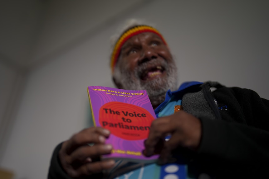 A man holds a Voice to Parliament book.
