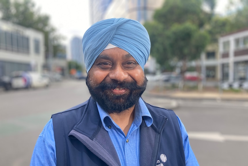 Kulivinder Singh stands smiling on a path on the side of the road.