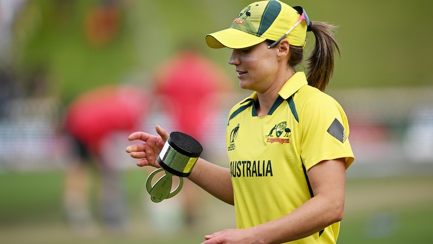 Ellyse Perry leaves a media conference flipping the tournament trophy in her hands