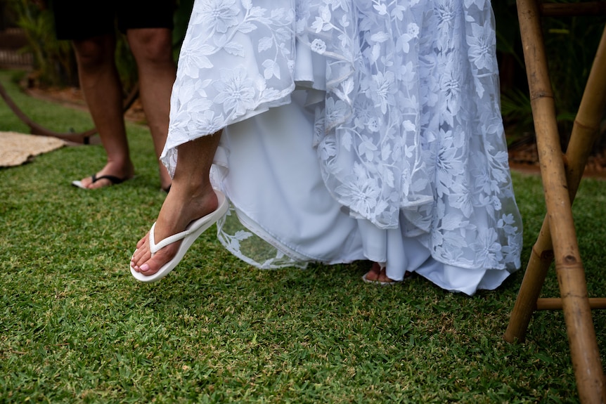  A woman showing off her flip flops under her white wedding dress 