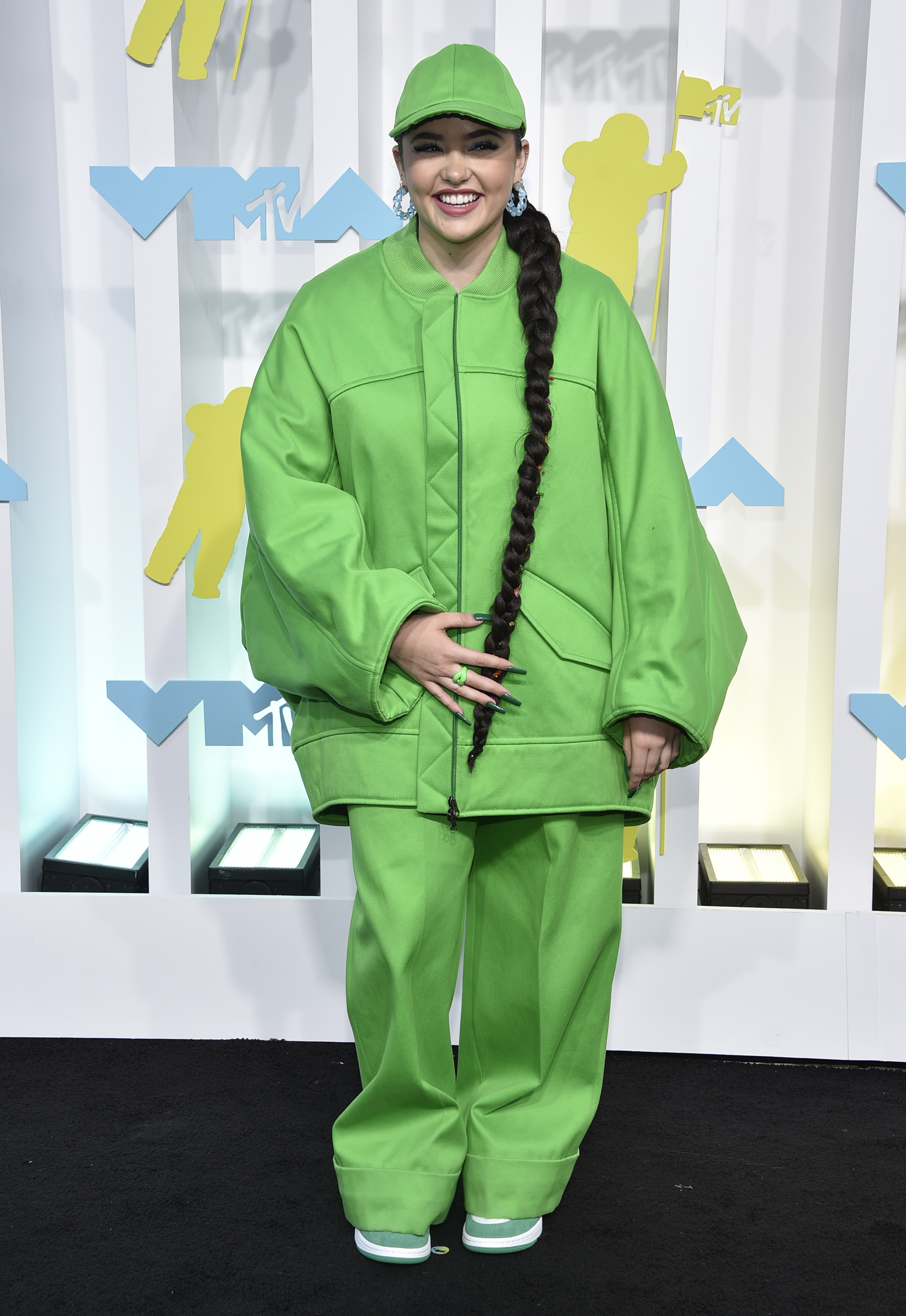 lauren spencer-smith poses and smiles on vmas arrivals carpet wearing full length oversized green track suit and matching cap