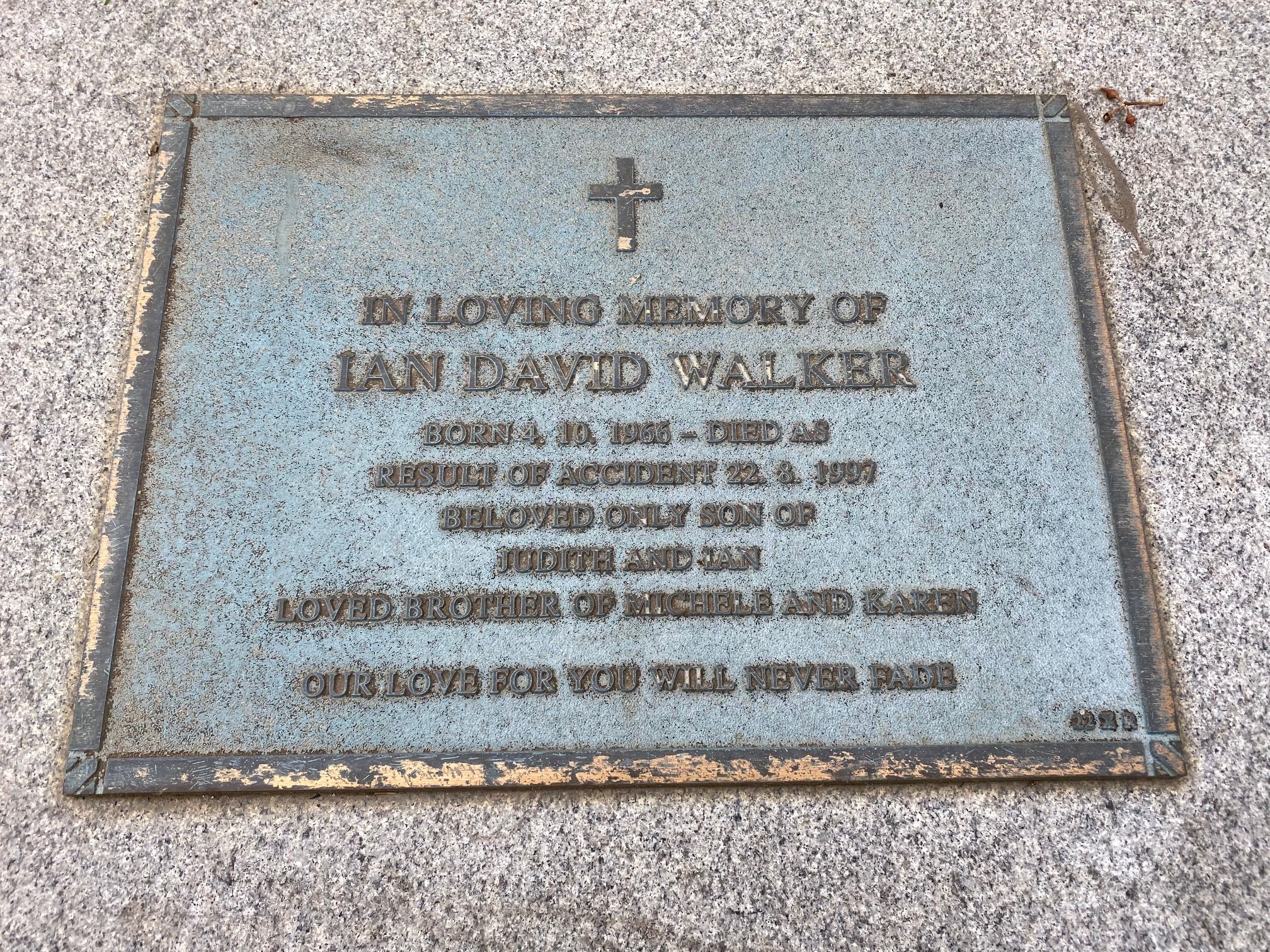 Headstone on white stone with a gold border. It reads: In loving memory of Ian David Walker.