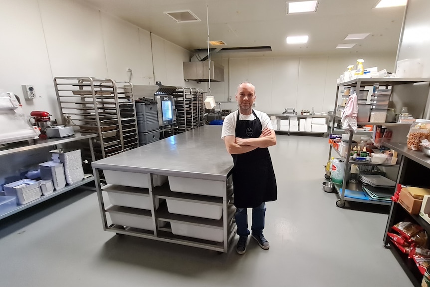 a man standing in an empty industrial kitchen