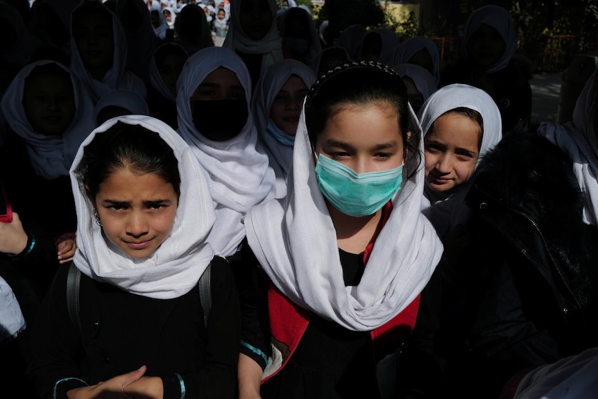 Three young girls, one wearing a mask. 