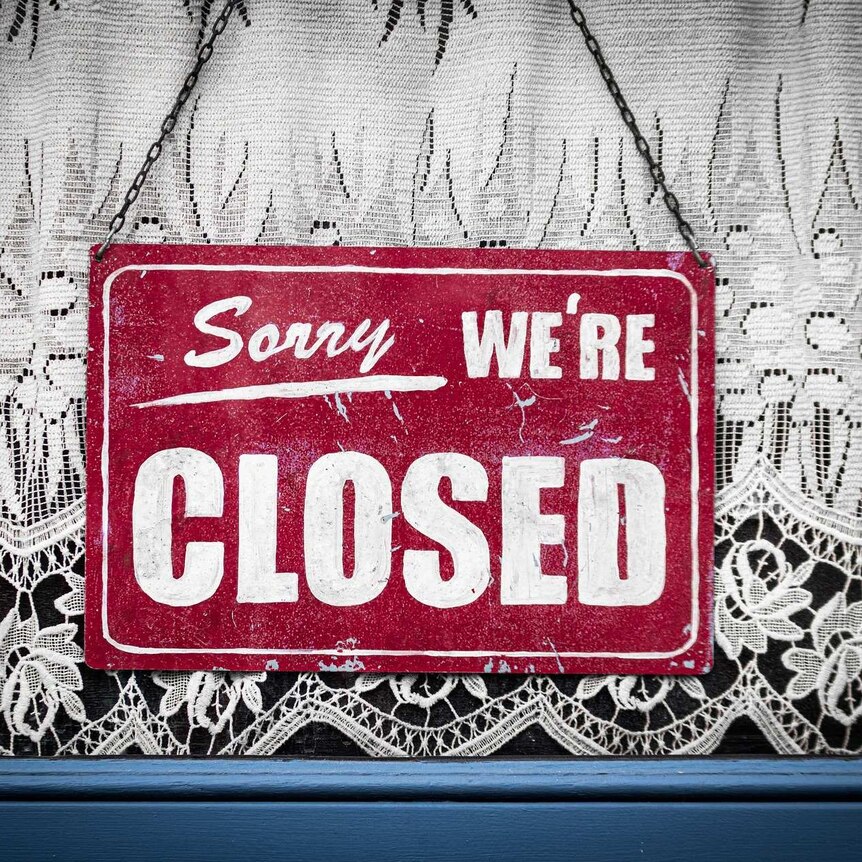 Sorry we're closed sign hanging in store window.