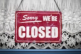 Sorry we're closed sign hanging in store window.