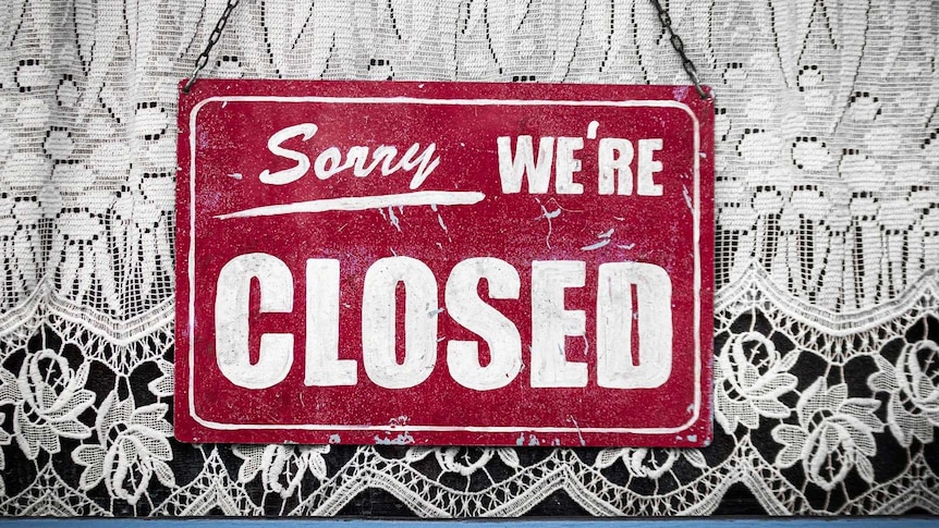 Sorry we're closed sign hanging in store window.