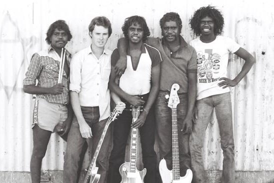 Warumpi Band members stand with their guitars.
