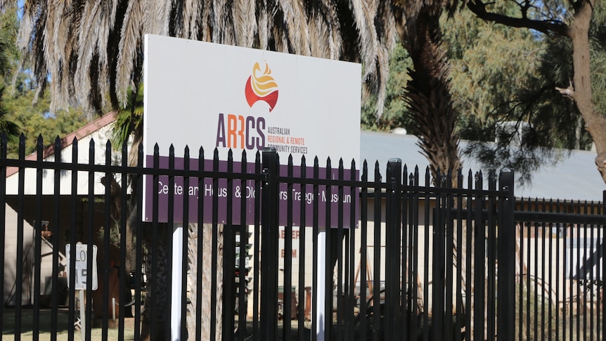 A black fence in front of sign which stands says ARRCS, Australian Regional and Remote Community Services.