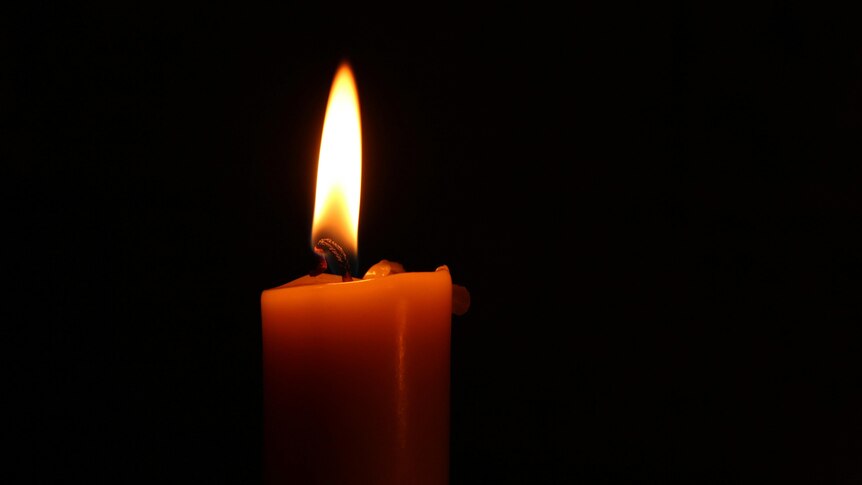  A close up of the tip of a burning candle which glows orange as the flame burns.