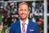 Promotional photo of Jess Glasgow smiling in a suit on The Bachelorette 2019 television program.