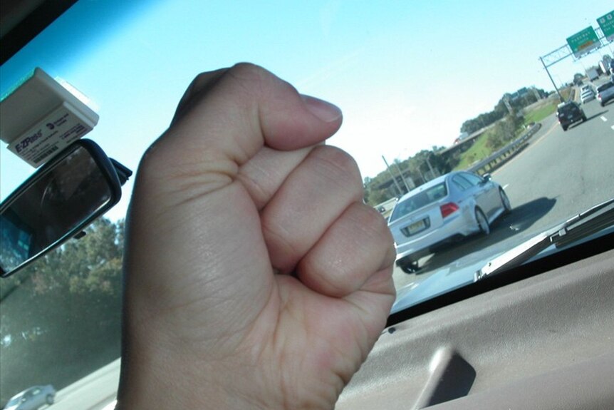 Hand in a fist in a car showing road rage