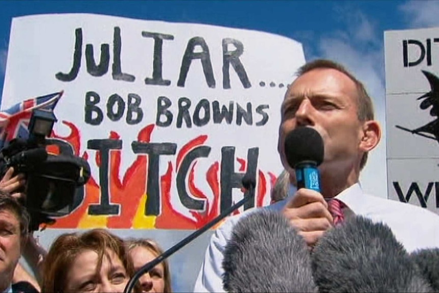Tony Abbott stands in front of an anti-Julia Gillard protest sign