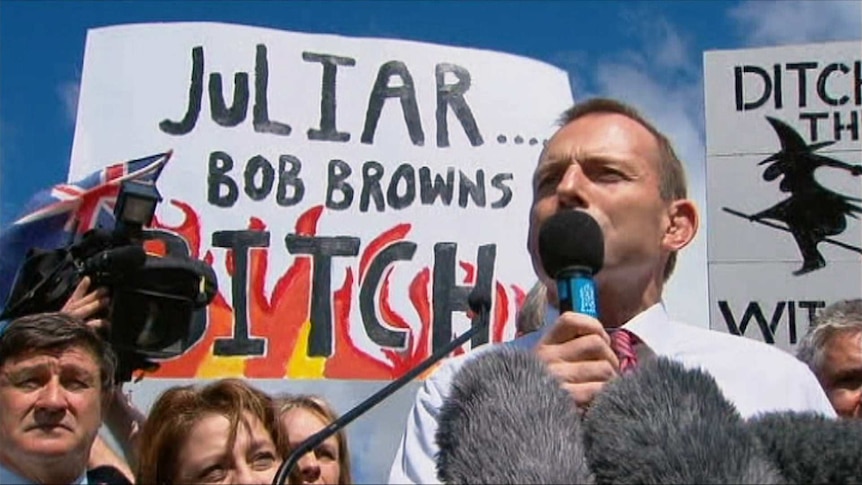 Tony Abbott stands in front of an anti-Julia Gillard protest sign