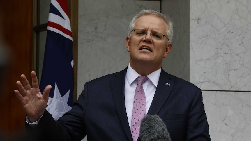 Scott Morrison addresses the media in a pink tie standing in a marble courtyard