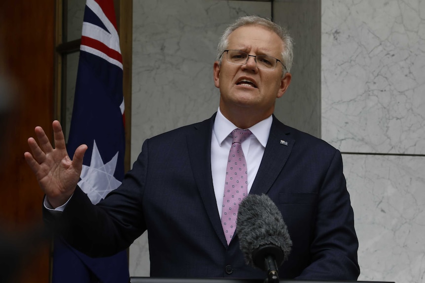 Scott Morrison addresses the media in a pink tie standing in a marble courtyard