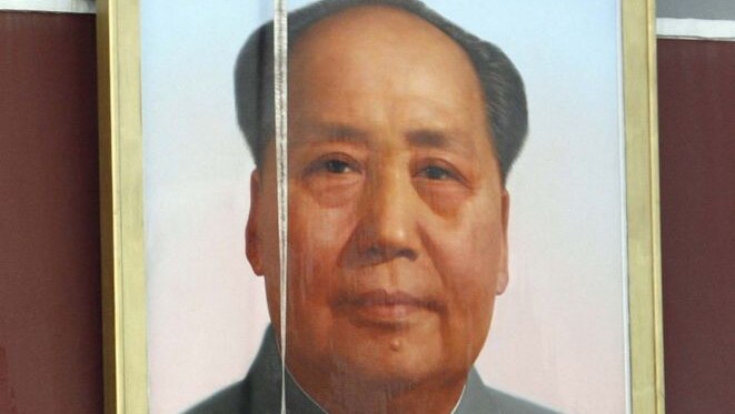 Workers clean the giant portrait of Mao Zedong in Tiananmen Square after a fire atttack