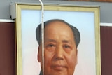 Workers clean the giant portrait of Mao Zedong in Tiananmen Square after a fire atttack