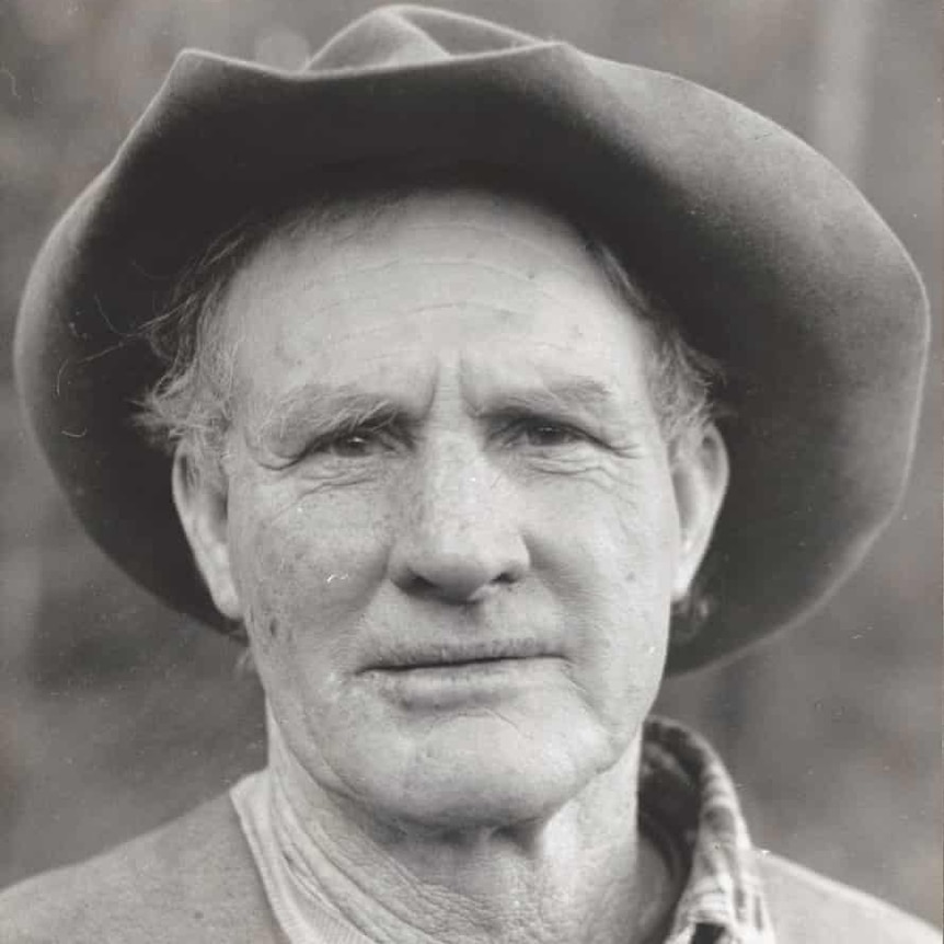 A black and white photo of a man wearing a battered old hat.