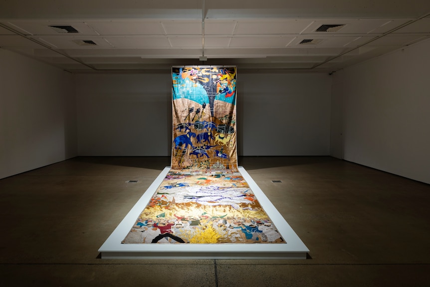 A large tapestry by Khadim Ali hanging in a gallery