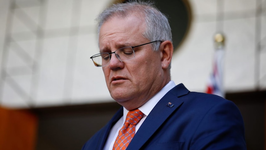 Scott Morrison looks down, seemingly distressed.