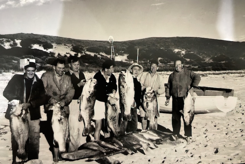 An historic image of a group of fishermen on the beach holding dhu fish.